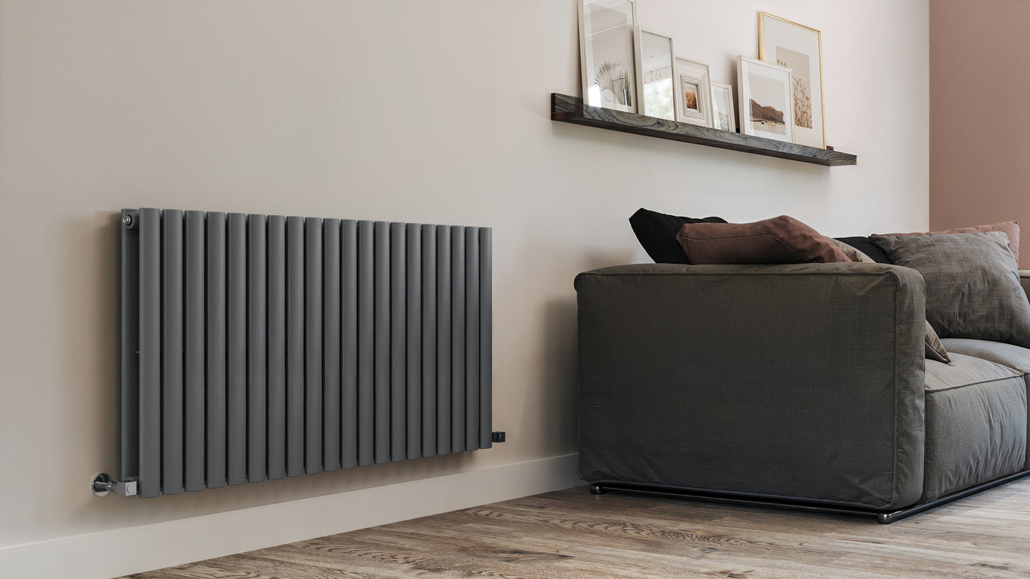 Modern radiator on a wall next to a gray sofa in a living room setting.