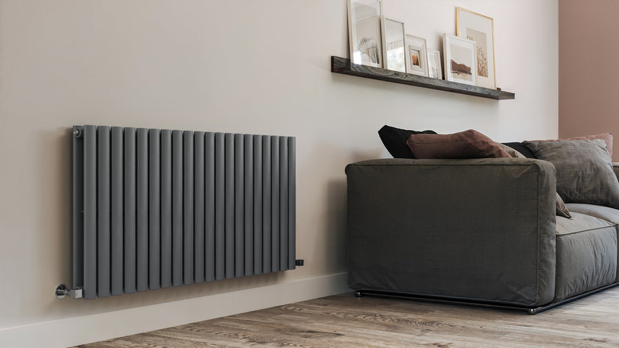 Modern radiator on a wall next to a gray sofa in a living room setting.