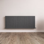 Black radiator on a white wall with wooden flooring
